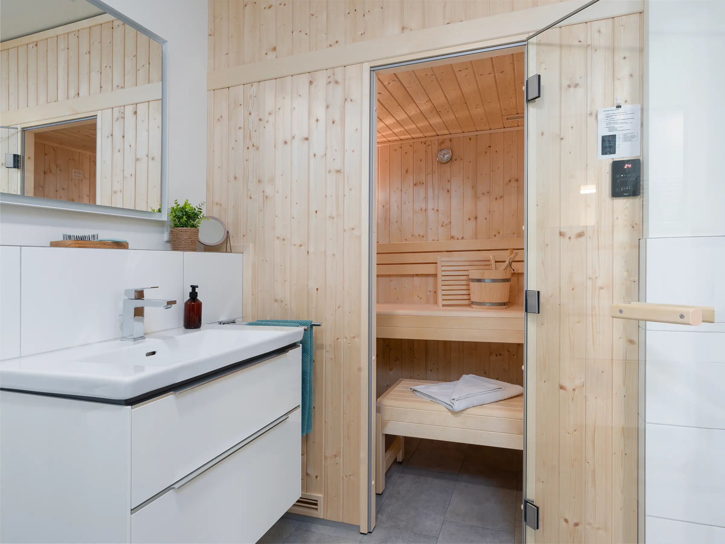 Modernes Badezimmer der Ferienwohnung Lotta mit beleuchtetem Spiegel, Waschtisch und Saunaeingang