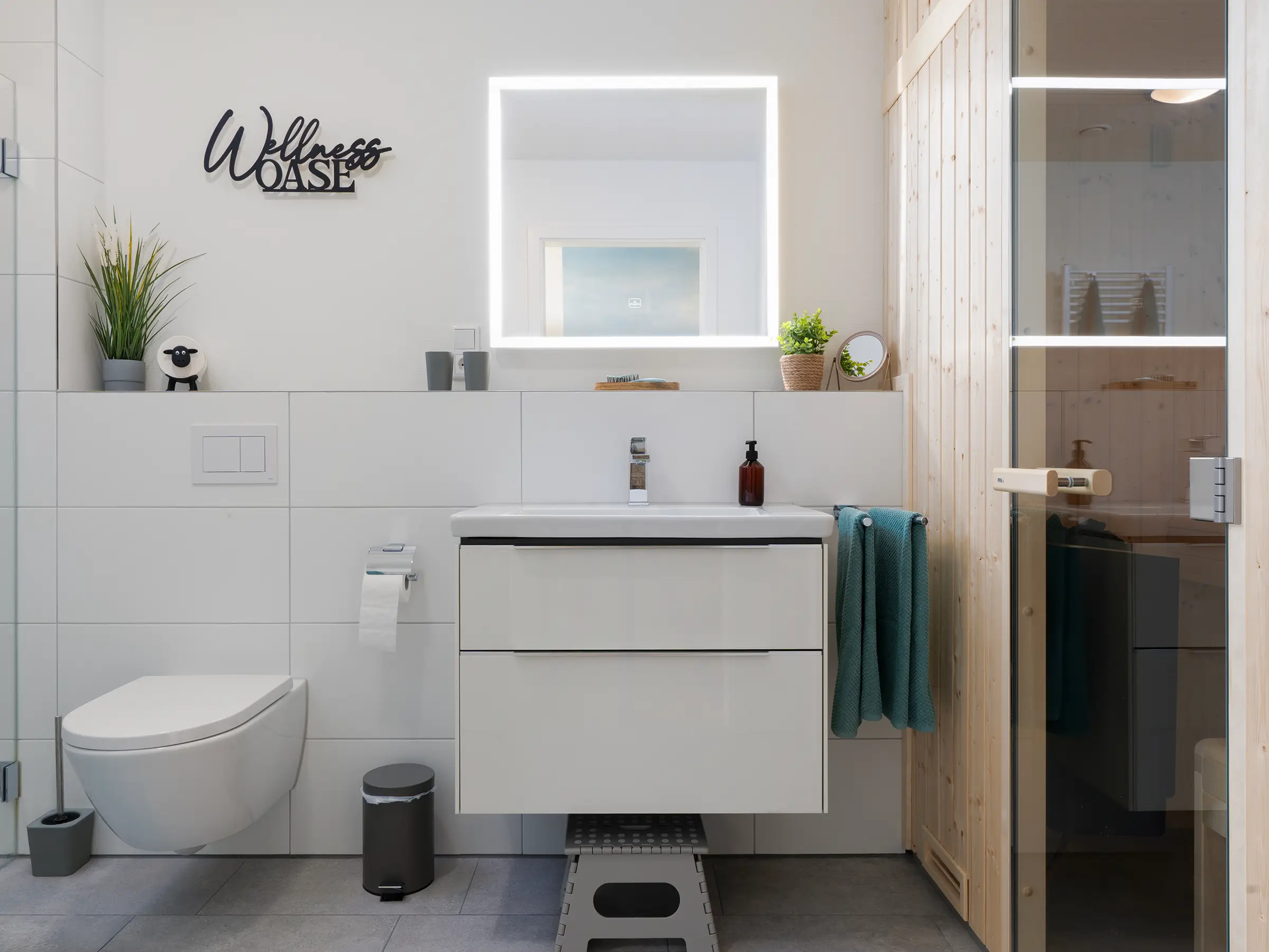 Modernes Badezimmer der Ferienwohnung Lotta mit beleuchtetem Spiegel, Waschtisch und Saunaeingang